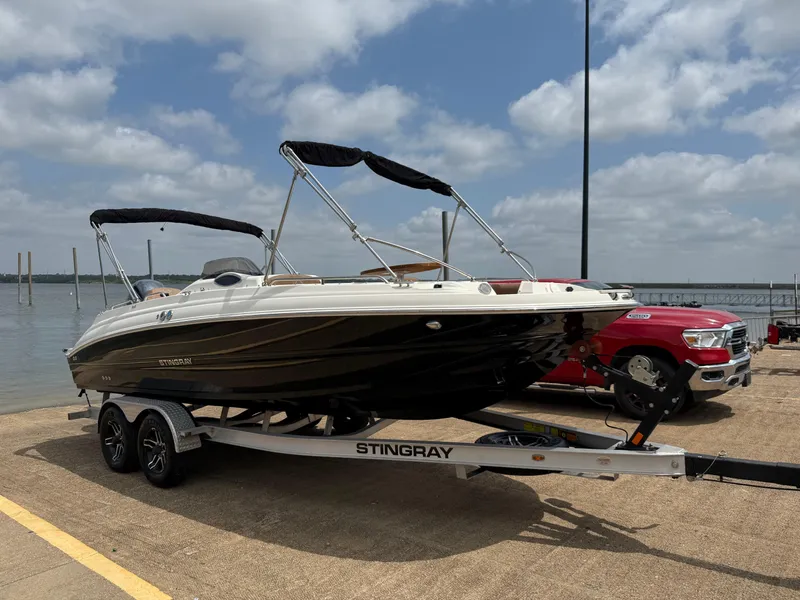 Slide: The Image of 2022 Stingray 212 SC boat on trailer by lake, under cloudy sky. - 33