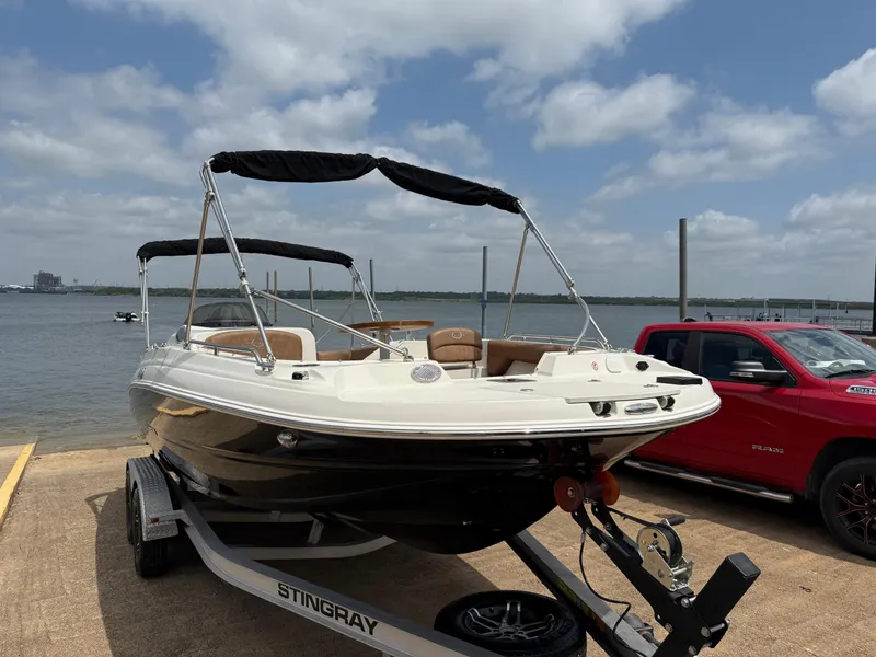 Slide: The Image of 2022 Stingray 212 SC boat on trailer by the water, under a partly cloudy sky. - 34