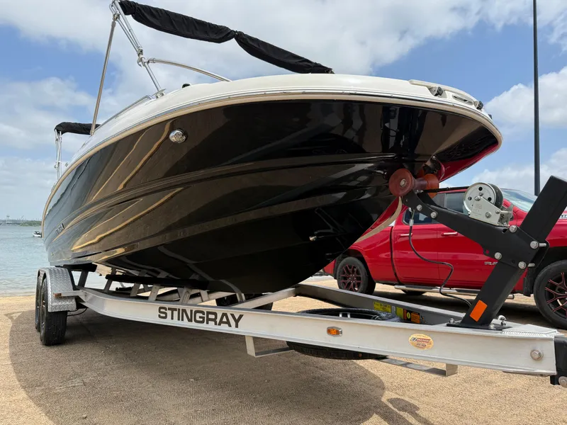 Slide: The Image of 2022 Stingray 212 SC boat on trailer, parked near water under a cloudy sky. - 35
