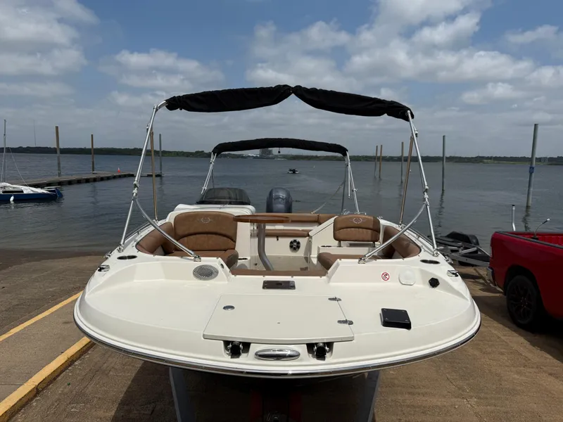 Slide: The Image of 2022 Stingray 212 SC boat docked by a lake under a cloudy sky. - 36