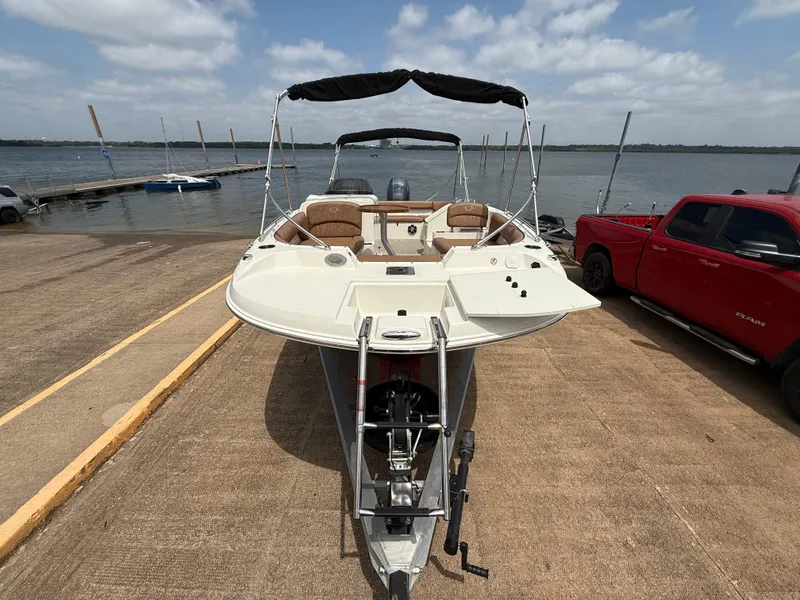 Slide: The Image of 2022 Stingray 212 SC boat on trailer by lake, with red truck nearby. - 37