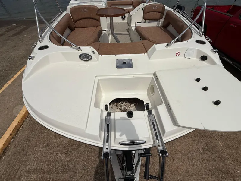 Slide: The Image of 2022 Stingray 212 SC boat with brown seating, table, and open storage compartment. - 38