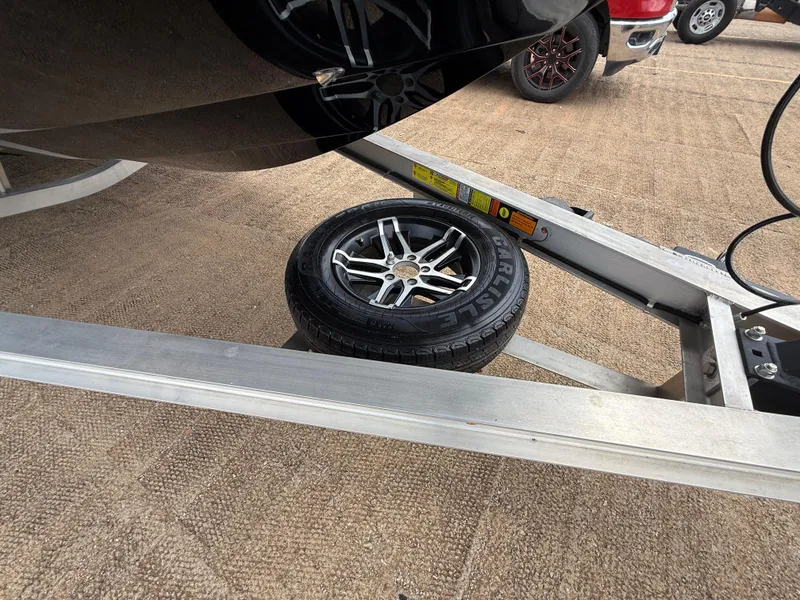 Slide: The Image of 2022 Stingray 212 SC boat trailer with spare tire on sandy ground. - 39