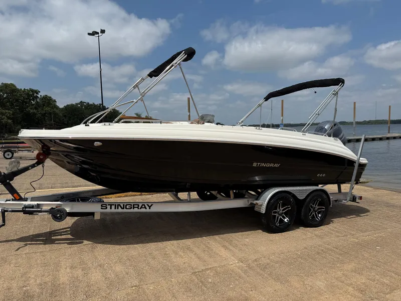 Slide: The Image of 2022 Stingray 212 SC boat on trailer by a lake under a cloudy sky. - 4
