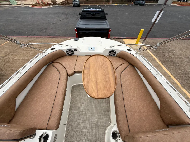 Slide: The Image of 2022 Stingray 212 SC boat interior with brown seating and wooden table, parked near a black truck. - 42