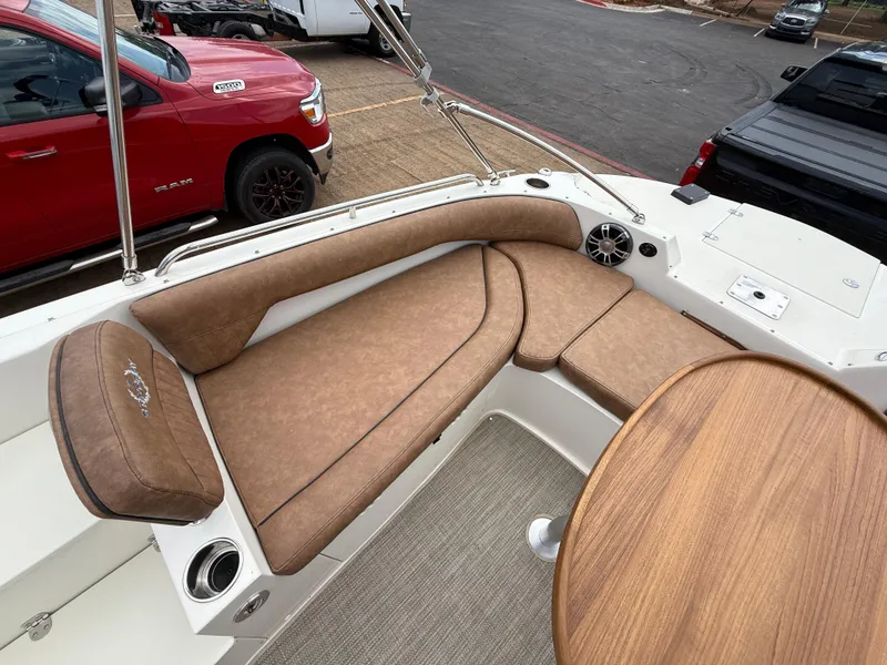 Slide: The Image of 2022 Stingray 212 SC boat interior with brown seating and wooden table. - 43