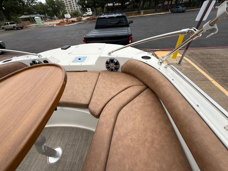 Slide: The Image of 2022 Stingray 212 SC boat interior with tan seating and wooden table. - 45