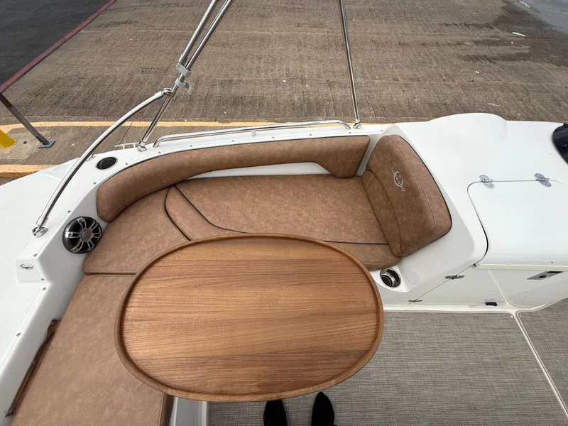 Slide: The Image of 2022 Stingray 212 SC boat interior with brown seating and wooden table. - 46