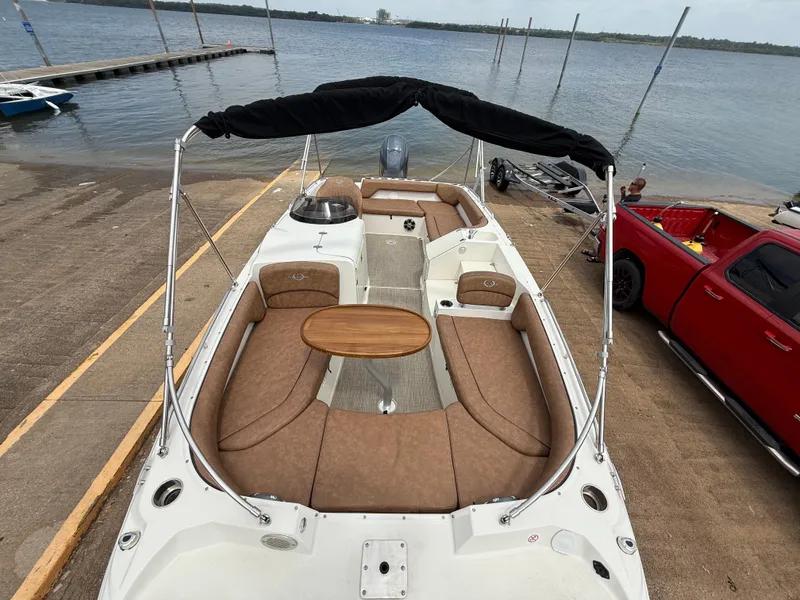 Slide: The Image of 2022 Stingray 212 SC boat with seating and table, docked near a red truck. - 47