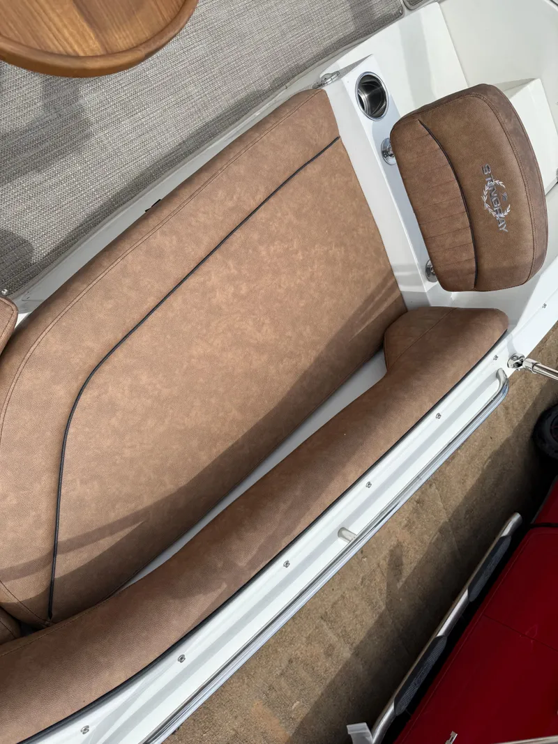 Slide: The Image of 2022 Stingray 212 SC boat interior with brown cushioned seating and wooden table. - 49