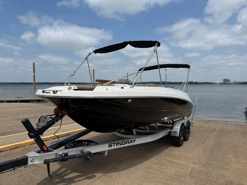 Slide: The Image of 2022 Stingray 212 SC boat on trailer by waterfront under cloudy sky. - 5