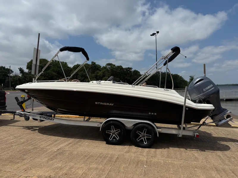 Slide: The Image of 2022 Stingray 212 SC boat on trailer, parked outdoors under cloudy sky. - 6