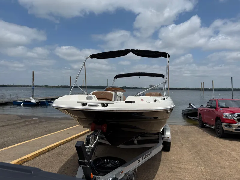 Slide: The Image of 2022 Stingray 212 SC boat on trailer by lake under cloudy sky. - 8
