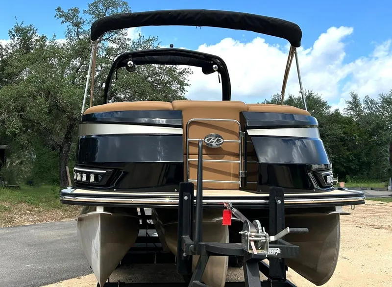 Slide: The Image of 2023 Harris Grand Mariner 230 pontoon boat on trailer, outdoors with trees and blue sky. - 11