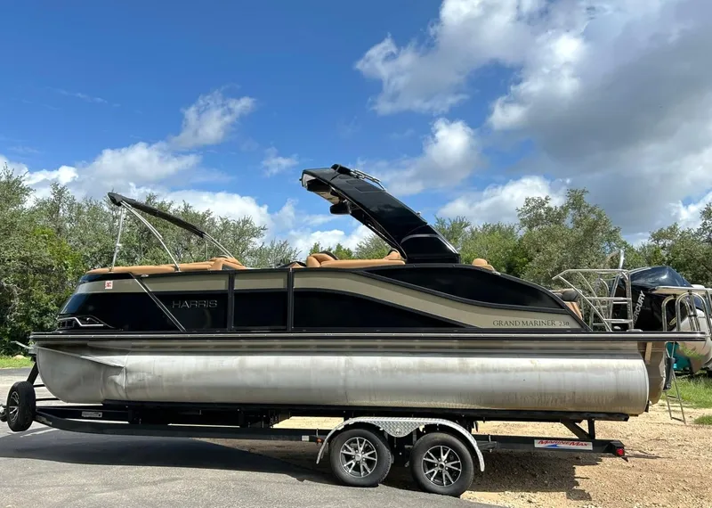 Slide: The Image of 2023 Harris Grand Mariner 230 pontoon boat on trailer under a blue sky. - 12