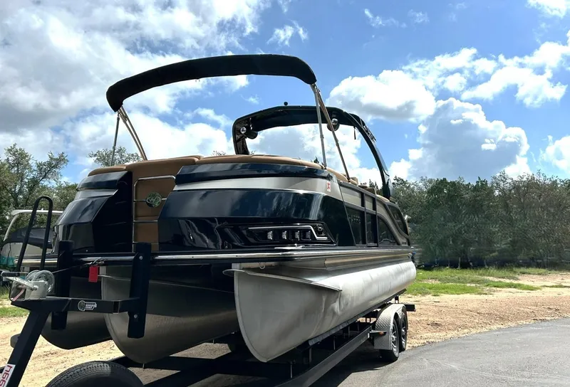 Slide: The Image of 2023 Harris Grand Mariner 230 pontoon boat on trailer under a partly cloudy sky. - 13