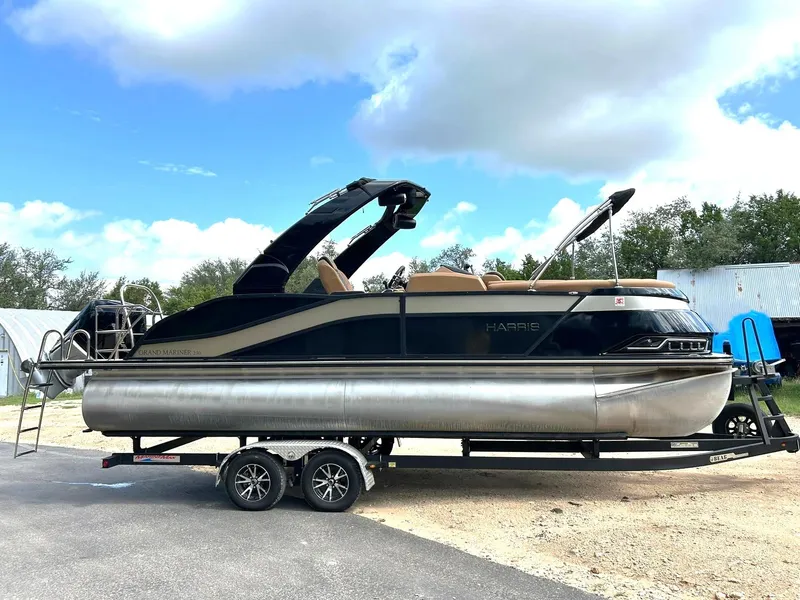 Slide: The Image of 2023 Harris Grand Mariner 230 pontoon boat on trailer under a partly cloudy sky. - 2