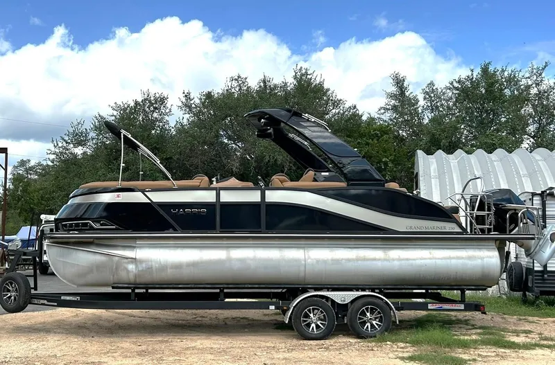 Slide: The Image of 2023 Harris Grand Mariner 230 pontoon boat on trailer, parked outdoors. - 3