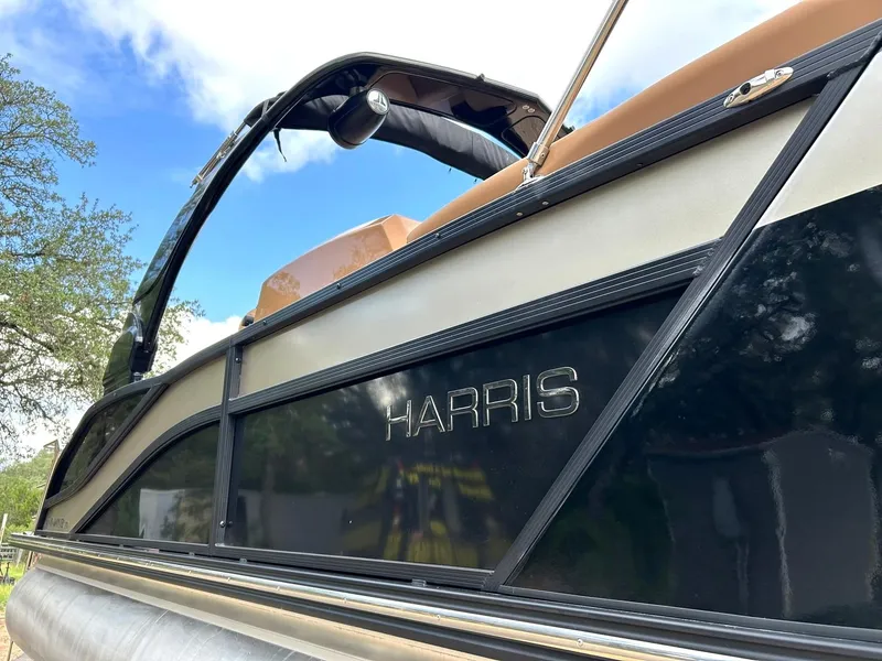 Slide: The Image of 2023 Harris Grand Mariner 230 pontoon boat, side view with logo, under blue sky. - 8