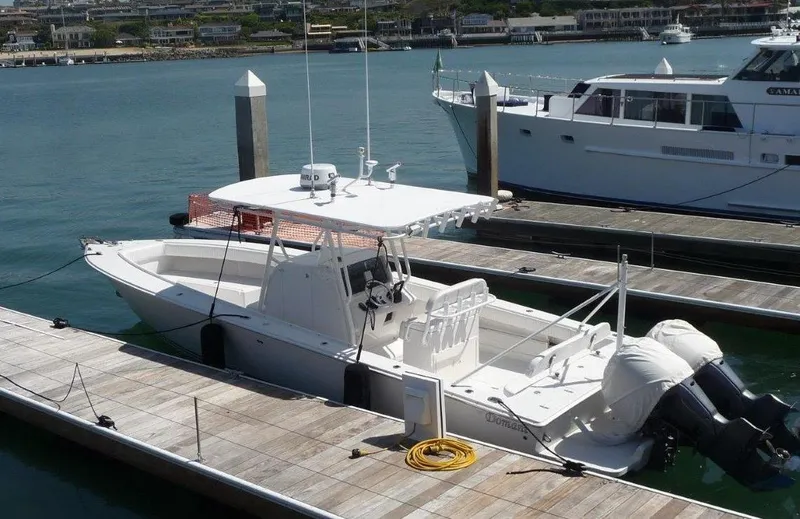 Slide: The Image of 2004 Jupiter Open Center Console boat docked at marina, featuring dual outboard motors. - 10