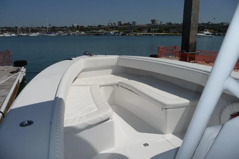 Slide: The Image of 2004 Jupiter Open Center Console boat with white seating, docked by the waterfront. - 2