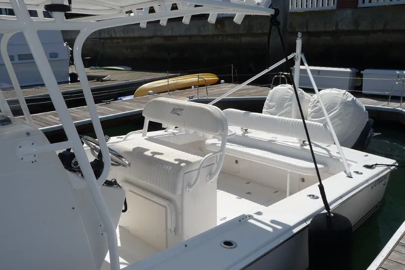 Slide: The Image of 2004 Jupiter Open Center Console boat with white seating and helm, docked at a marina. - 4