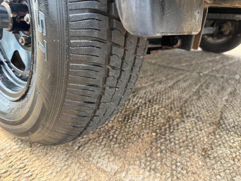 Slide: The Image of Close-up of a 2003 Skeeter SX190 trailer tire on textured ground. - 11