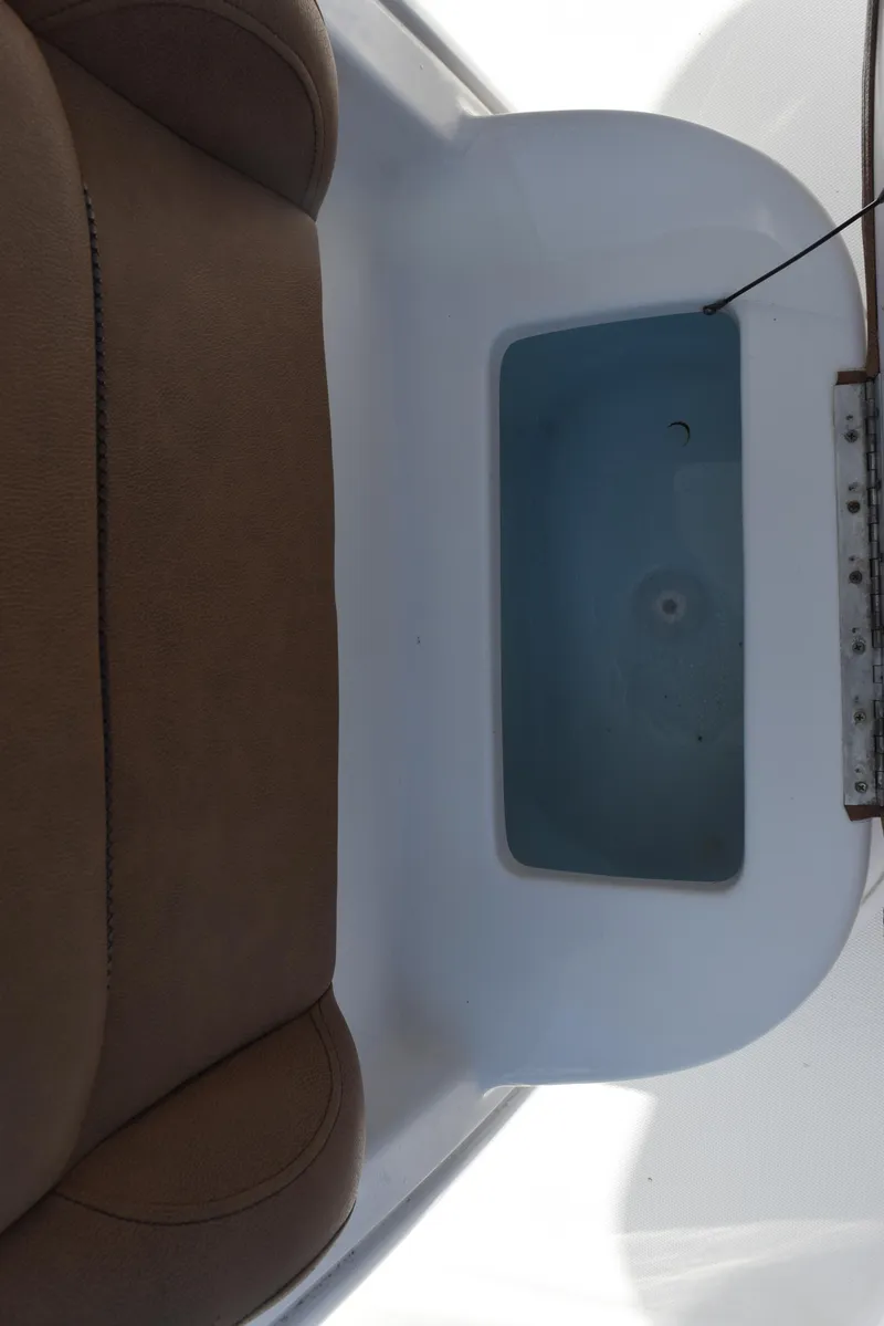 Slide: The Image of 2019 Sea Hunt Ultra 235 SE boat interior with brown seating and storage compartment. - 16