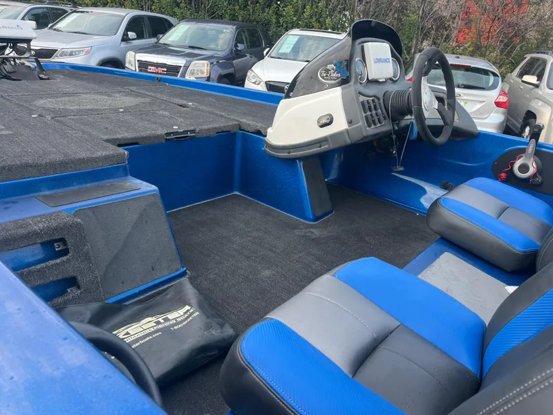 Slide: The Image of 2018 Skeeter ZX190 boat interior with blue and gray seating, steering console, and parked cars. - 19