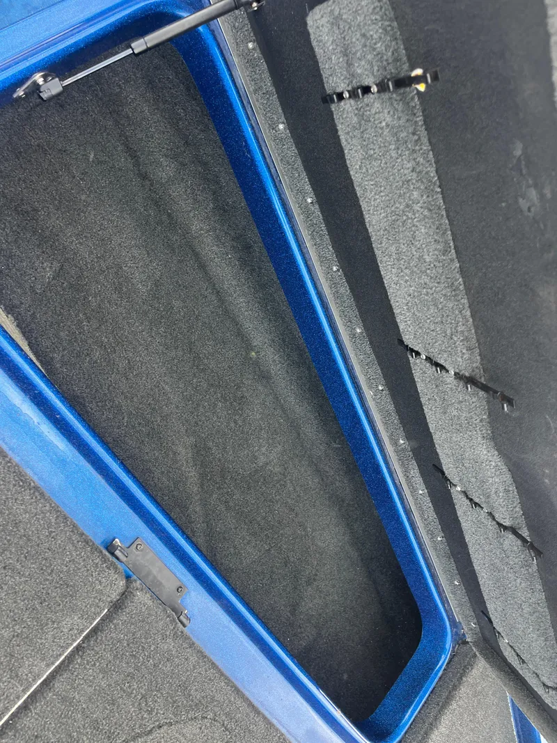 Slide: The Image of Open storage compartment in a 2018 Skeeter ZX190 boat, featuring blue trim and carpeted interior. - 36