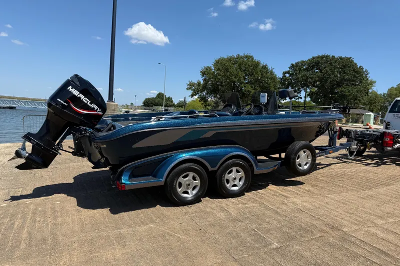 Slide: The Image of 1999 Ranger 620VS Fisherman boat on trailer, parked near a lake under a clear blue sky. - 22
