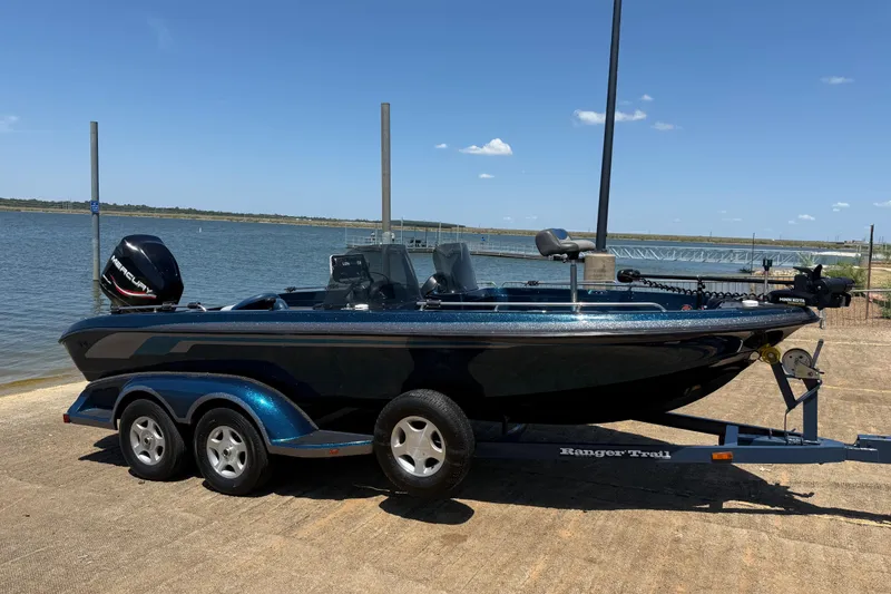 Slide: The Image of 1999 Ranger 620VS Fisherman boat on trailer by a lake under clear blue sky. - 24