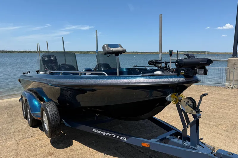 Slide: The Image of 1999 Ranger 620VS Fisherman boat on trailer by the water, clear sky background. - 25