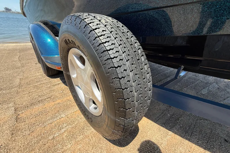 Slide: The Image of 1999 Ranger 620VS Fisherman trailer tire on a boat ramp by the water. - 56