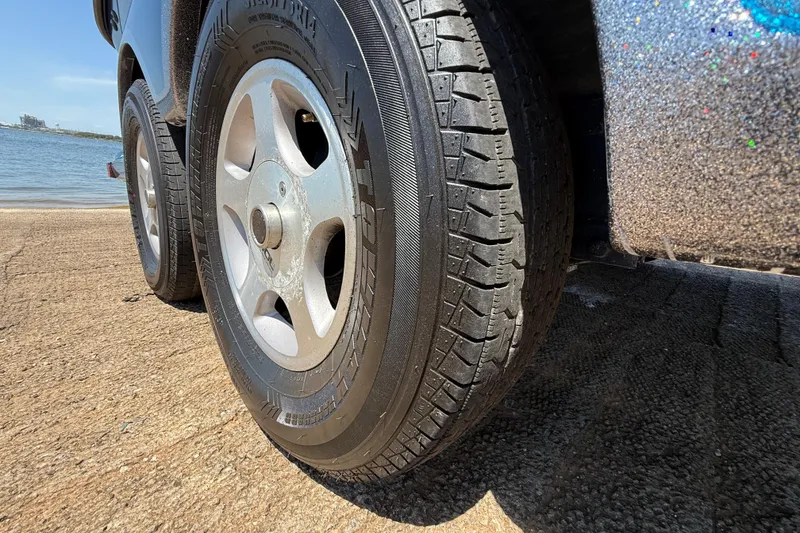 Slide: The Image of Close-up of 1999 Ranger 620VS Fisherman trailer wheels near a waterfront. - 59
