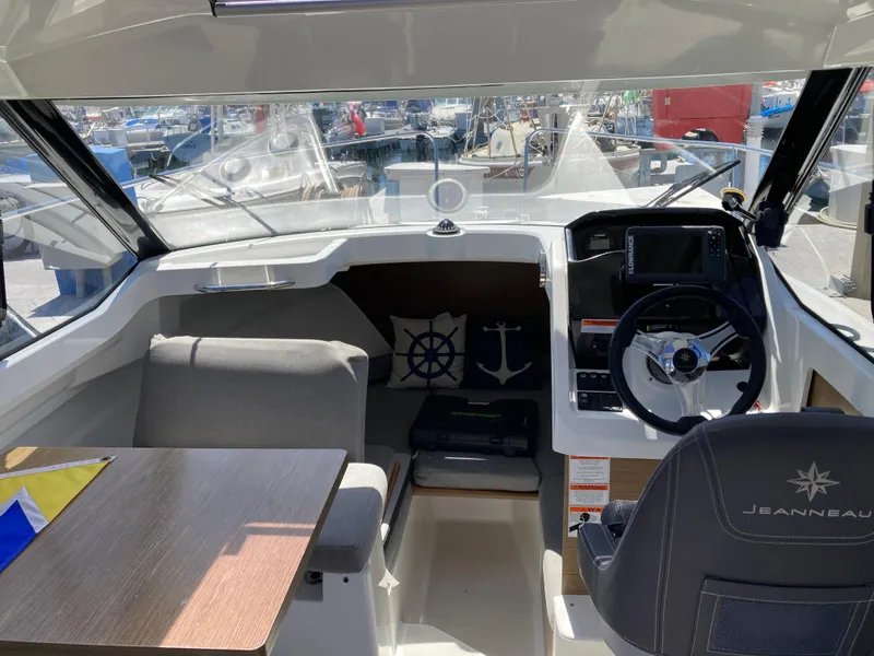 Slide: The Image of Interior of 2018 Jeanneau NC 695 boat, featuring helm, seating, and nautical decor. - 12