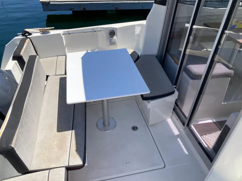 Slide: The Image of 2018 Jeanneau NC 695 boat interior with seating and table, docked by the water. - 14