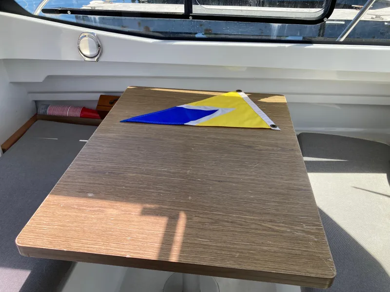 Slide: The Image of Interior of 2018 Jeanneau NC 695 with a table and nautical flag. - 16