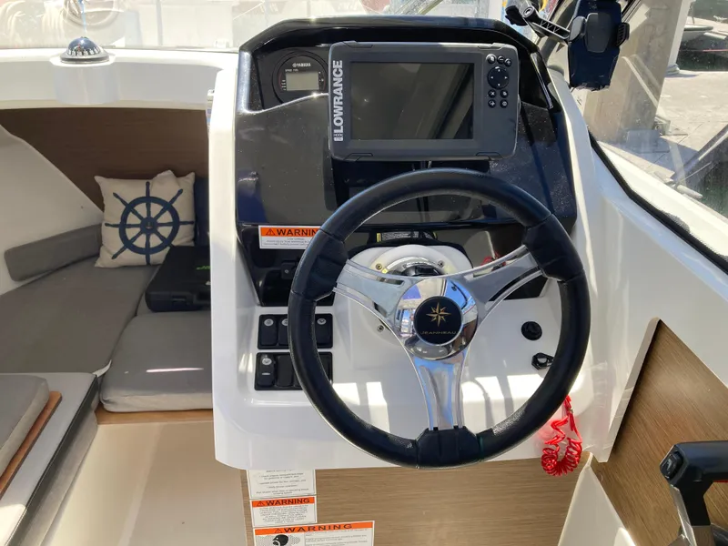 Slide: The Image of 2018 Jeanneau NC 695 boat helm with steering wheel and navigation equipment. - 17