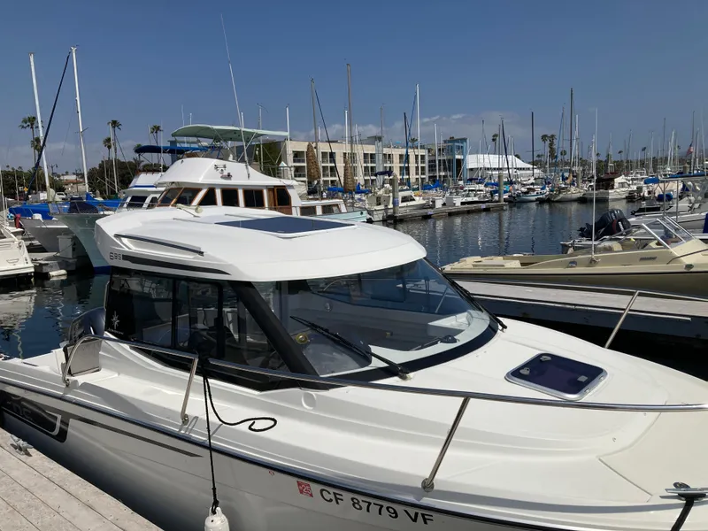 Slide: The Image of 2018 Jeanneau NC 695 boat docked in a marina with other vessels. - 2