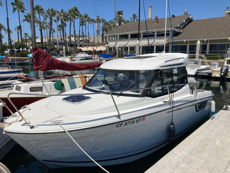 Slide: The Image of 2018 Jeanneau NC 695 boat docked at a marina with palm trees in the background. - 5