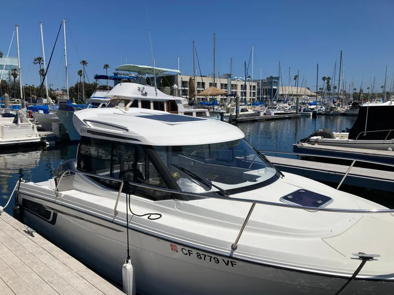 Slide: The Image of 2018 Jeanneau NC 695 boat docked in a marina under clear blue skies. - 6