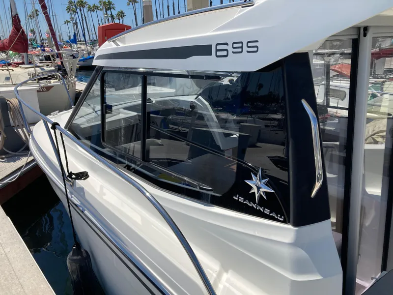 Slide: The Image of 2018 Jeanneau NC 695 boat docked at marina, showcasing sleek design and branding. - 7