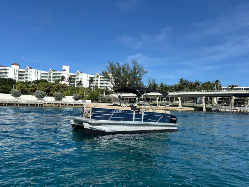 The Image of 2021 Godfrey Sweetwater pontoon boat on clear blue water near waterfront buildings. - 1