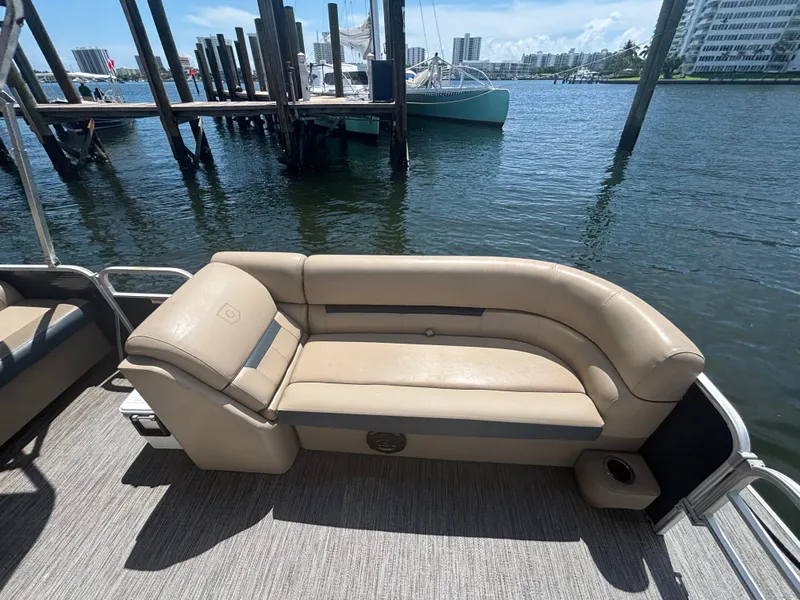 Slide: The Image of 2021 Godfrey Sweetwater boat with beige seating, docked by the water. - 10