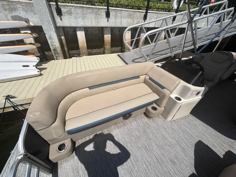 Slide: The Image of 2021 Godfrey Sweetwater boat interior with beige seating and helm, docked at marina. - 11