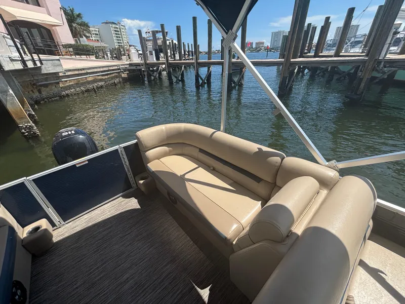 Slide: The Image of 2021 Godfrey Sweetwater pontoon boat with tan seating, docked by waterfront buildings. - 13