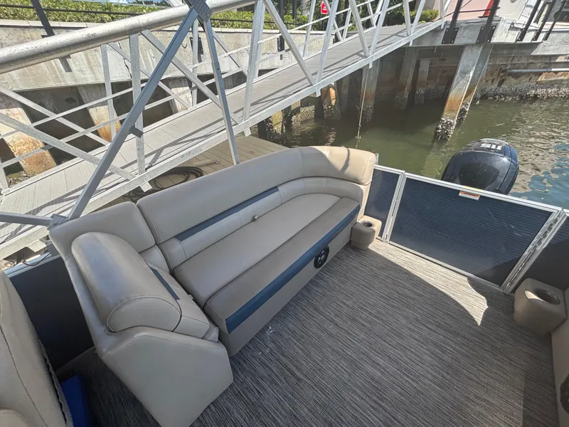 Slide: The Image of 2021 Godfrey Sweetwater pontoon boat interior with beige seating and dock view. - 14