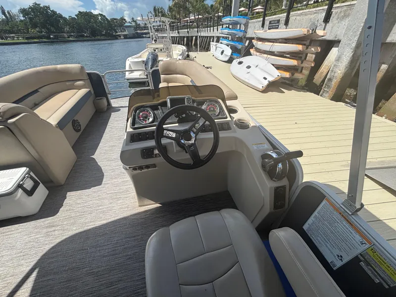 Slide: The Image of 2021 Godfrey Sweetwater boat interior with steering wheel, docked by the water. - 15