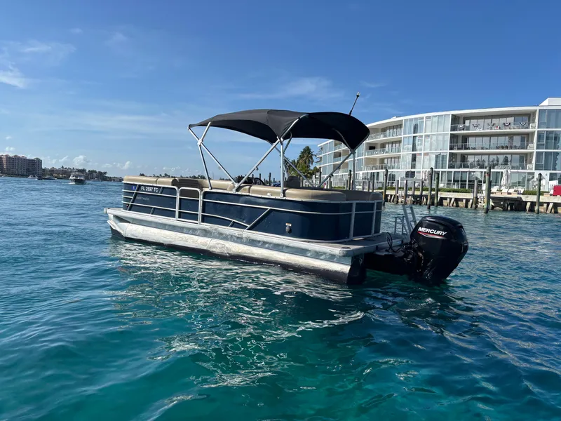 Slide: The Image of 2021 Godfrey Sweetwater pontoon boat on clear blue water near modern waterfront buildings. - 3